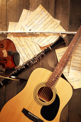 Wall Mural - Acoustic guitar, soprano saxophone, violin, flute and note sheets on wooden background