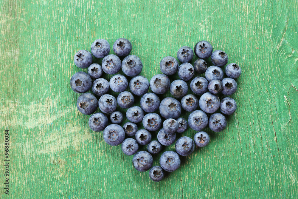 Heart shaped bilberries on old wooden background