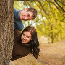Couple Peeking Out From Behind A Tree