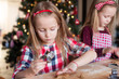 © travnikovstudio - Adorable girls baking gingerbread cookies for Christmas at home kitchen