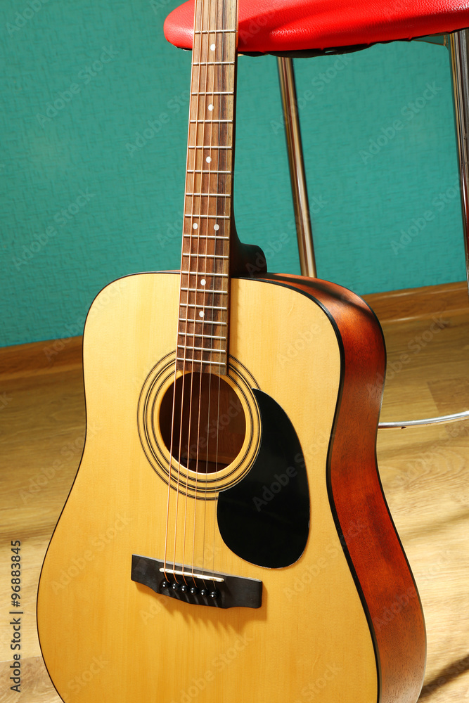 Guitar with bar stool on the floor against blue background in the studio