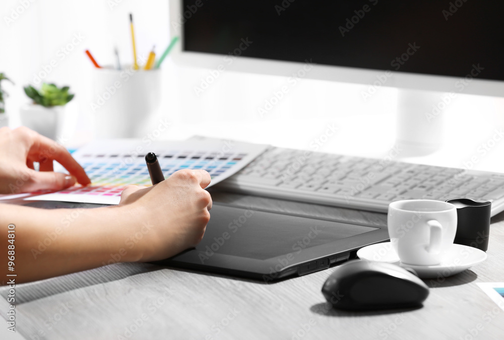 Female hand drawing on the graphic tablet in the office, close-up