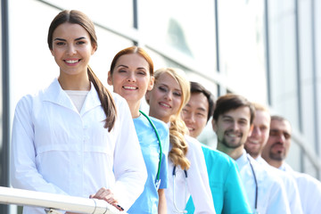 Poster - Smiling medics team standing in a row near the clinic