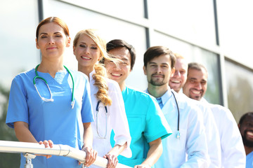 Canvas Print - Smiling medics team standing in a row near the clinic