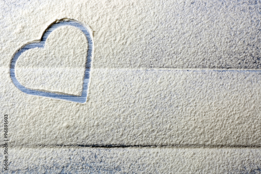 Heart of flour on wooden background