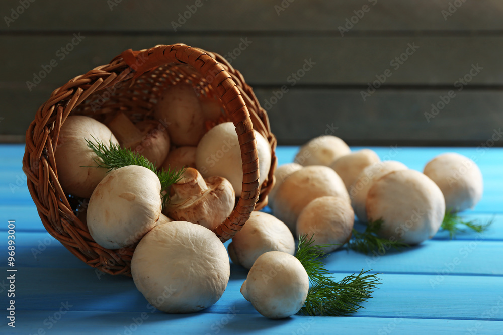 Mushrooms in basket on color wooden surface