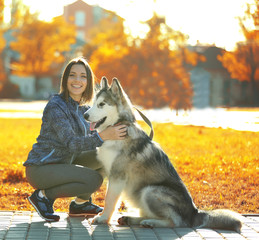 Happy young woman walking with her dog in park