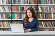 © ImageFlow - smiling young girl sitting at a desk in the library working with