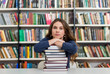 © ImageFlow - young girl sitting at a desk in the library with her arms on a b