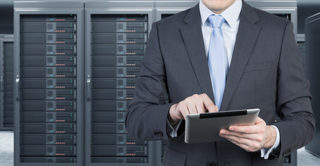 young man with a tablet in front of server for data storage, pro