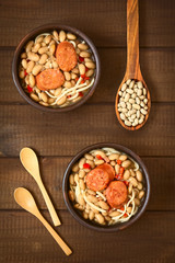 Wall Mural - Traditional Chilean dish called Porotos con Riendas (English: beans with reins), made of cooked beans, linguine (flat spaghetti) and served with fried sausage, photographed on wood with natural light