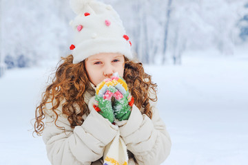 Wall Mural - Little Girl warms the hands of breath in winter park.