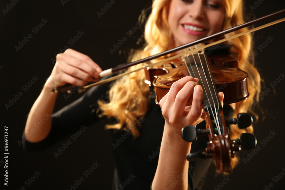 Musician plays violin on black background, close up