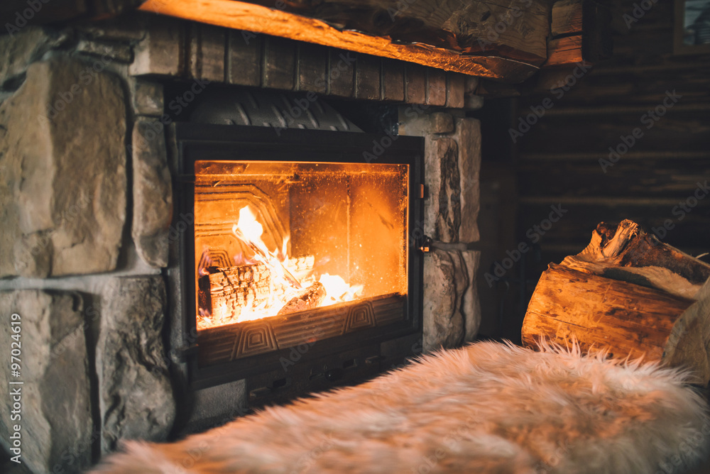Warm cozy fireplace with real wood burning in it. Cozy winter concept. Christmas and travel background with space for your text - obrazy, fototapety, plakaty 