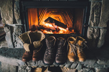 Winter Boots In Front Of A Fireplace. Family Vintage Folk Boots Drying Near The Fireside. Warm Cozy Fireplace In The Authentic Chalet. Hipster Shoes Getting Warm Near The Burning Fire In A Cabin