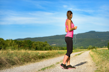 Wall Mural - Attractive female runner holding headphones, ready for her workout