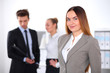 © rogerphoto - Pretty businesswoman in office with colleagues in the background