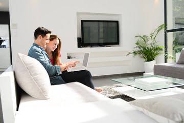 cheerful young couple man and woman in sofa at home with laptop computer