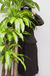 Businesswoman hiding behind plant with binoculars