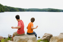 Father And Son Throwing Rocks Into Lake