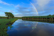 Part rainbow over North Queensland cane field with reflection in the water.