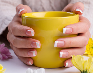 Fotomurales - Woman holds a yellow cup close up.