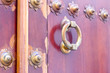 Golden color doorknocker in a brown wooden door