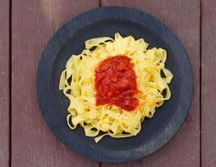 Tagliatelle with tomato sauce in wooden plate