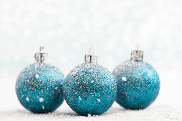 Christmas ball in the snow on blurred light background. A holiday card. Traditional Christmas decorations.