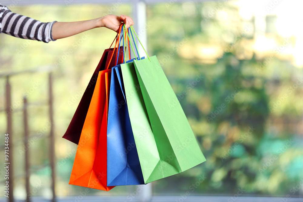 Female hand holding shopping bags on defocused background