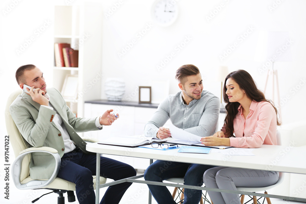 Happy family with estate agent,  in bright office