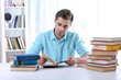 © Africa Studio - Young man reading book at table in room