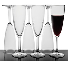 Set Of Six Wine Glasses Standing In A Row, Three Glasses Upside Down, One Glass Of Red Wine. Isolated On White Background.