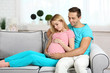 © Africa Studio - Young pregnant woman with husband on sofa in room