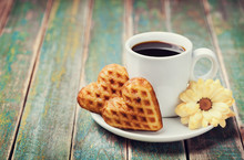 Waffle Biscuits In Shape Of Heart With Cup Of Coffee And Flower On Rustic Background For Valentines Day, Vintage Toned