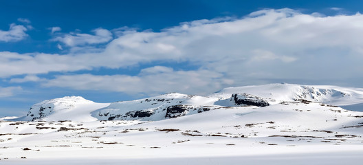 Wall Mural - Snowy mountain range in the sunlight. Clouds, blue sky. Winter.  Finse, Norway.