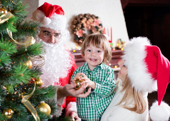 Child boy helps mother and father to decorate family Christmas tree