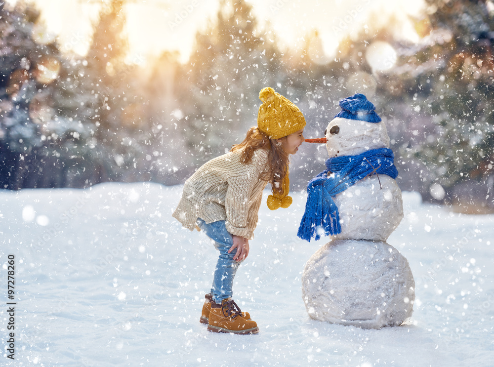 girl playing with a snowman - obrazy, fototapety, plakaty 