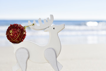 Wall Mural - christmas ball in the antler of a wooden reindeer on the beach