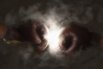 Two old brown boxing gloves hit together