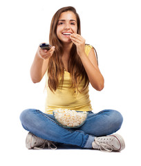 young woman eating popcorn and watching the tv on white