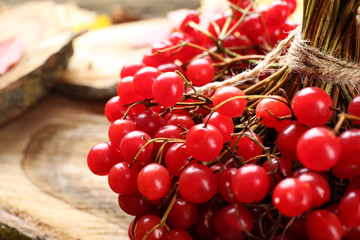 Wall Mural - Autumn composition: bunch of viburnum and colourful leaves on wooden table, close up