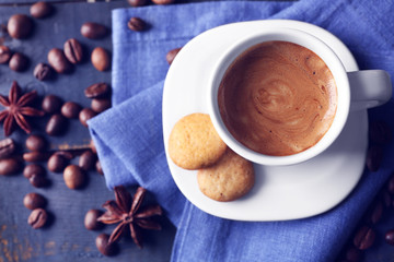 Cup of coffee with spices on wooden table background