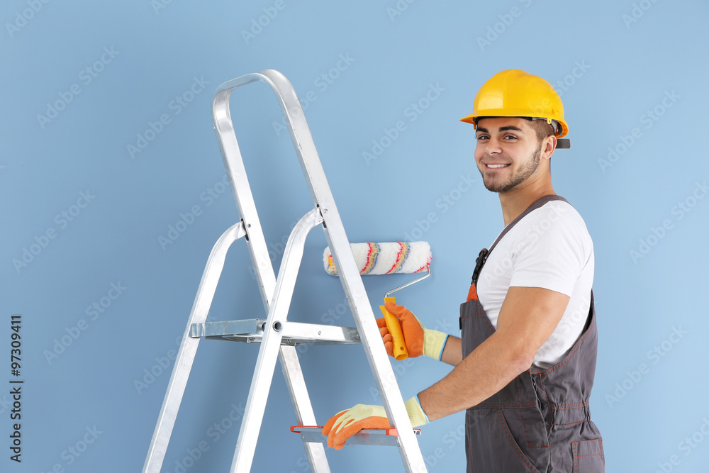 Young worker renewing apartment on wall background