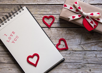 valentine gift box, notebook and red heart shape tag on wooden b