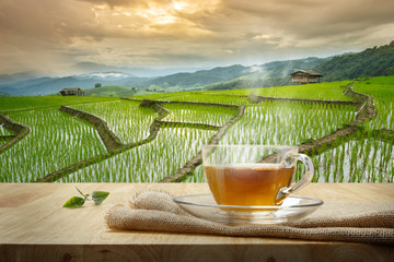 Wall Mural - Cup of hot tea with sacking on the wooden table and the rice fie