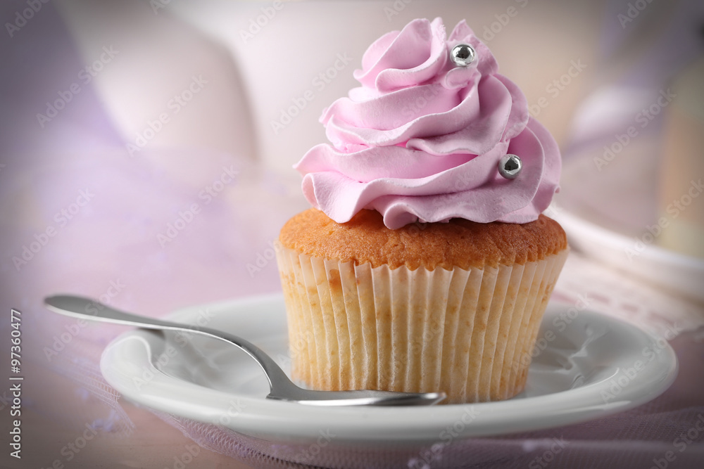 Tasty cupcake on saucer, on light background