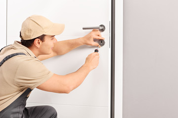 Wall Mural - Young locksmith installing a lock on a door