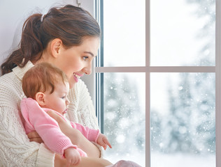 Mother and baby hugging near window