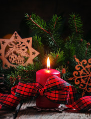 Christmas composition with burning red candles tied with plaid r